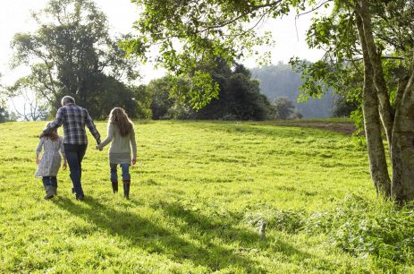 Family walking up a grassy hill together